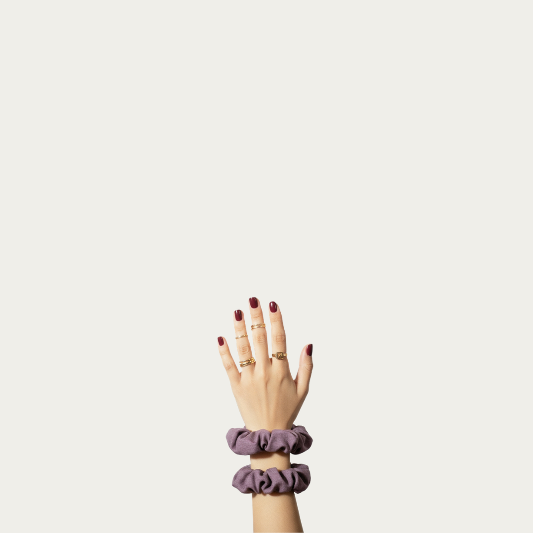 raised hand with red manicure and gold rings wearing linen scrunchies