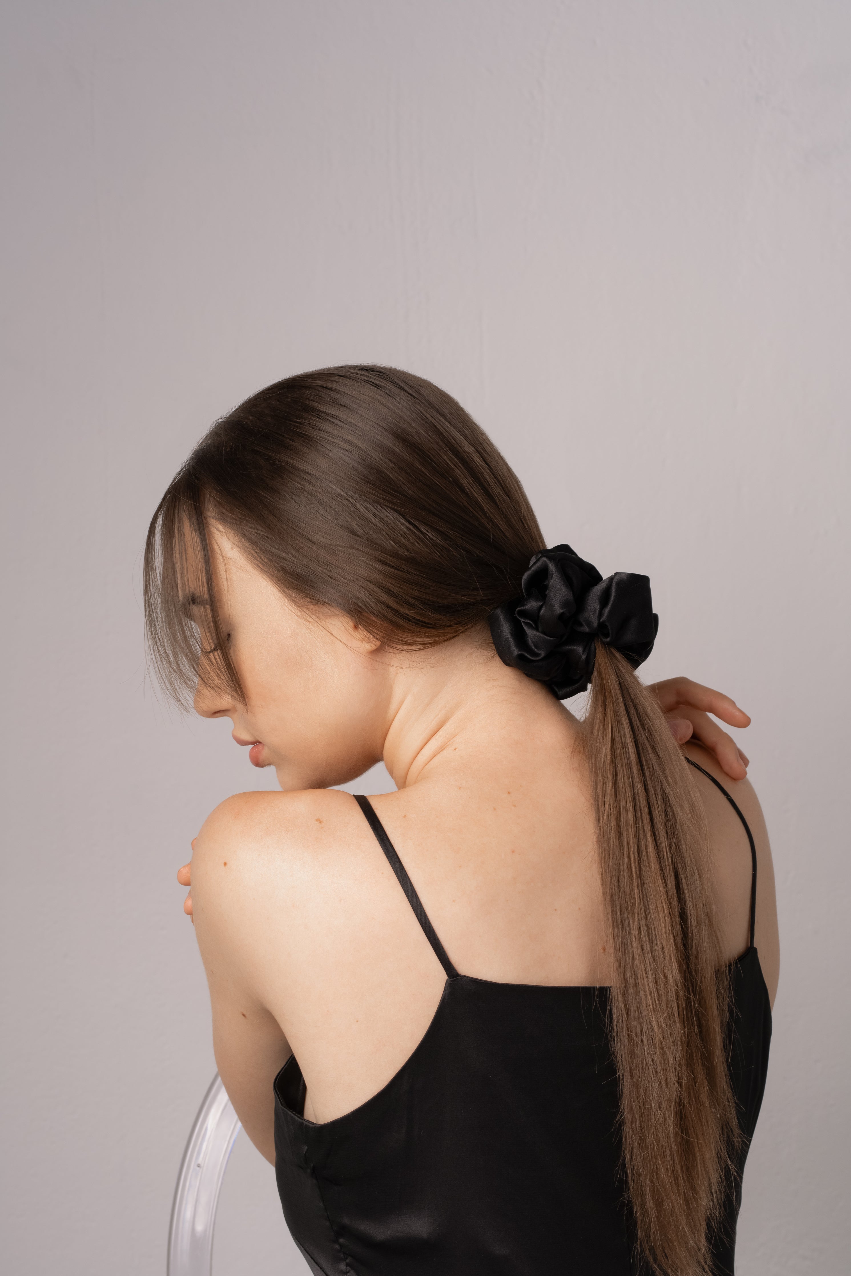 seated long haired model wearing a black silk scrunchie