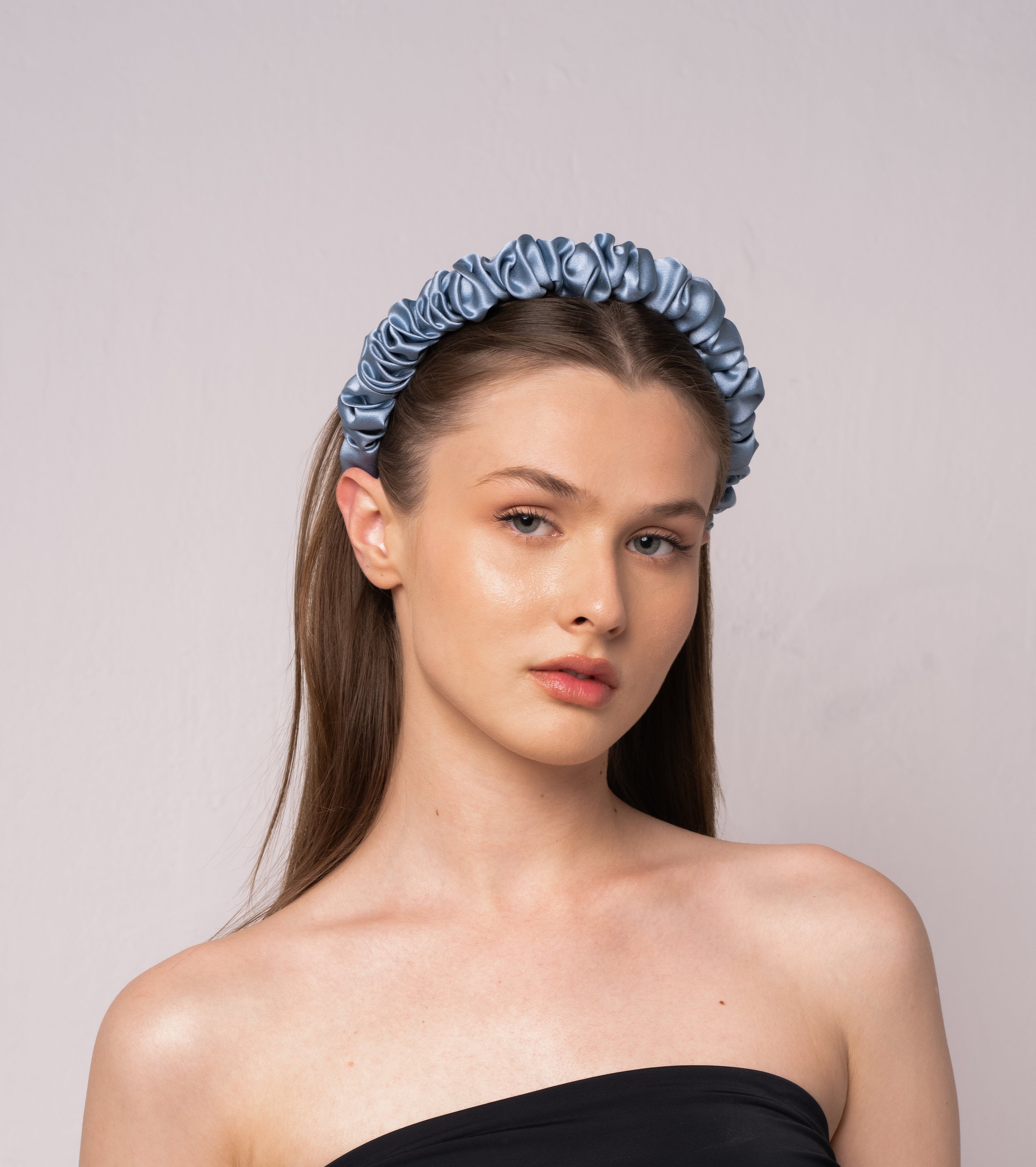Woman wearing a silk blue headband against a plain background