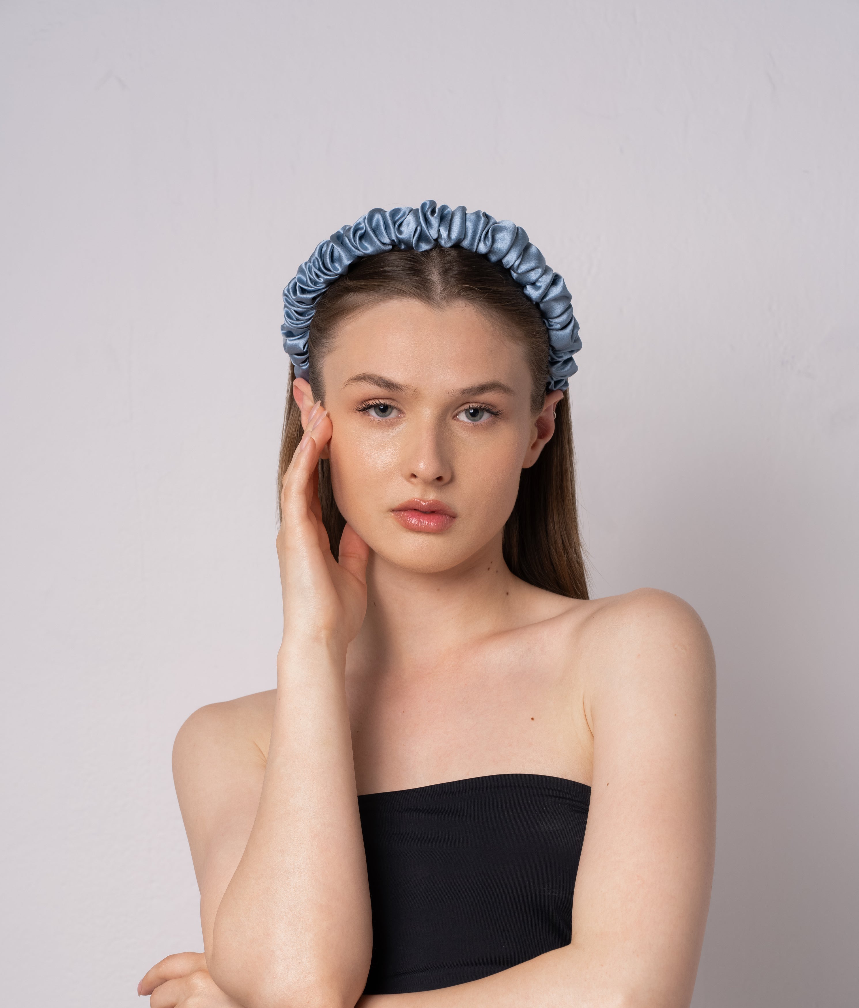 Woman wearing a silk blue headband against a plain background